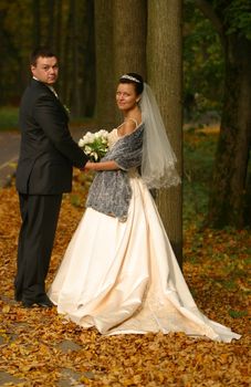 Beautiful the bride and the groom in autumn park