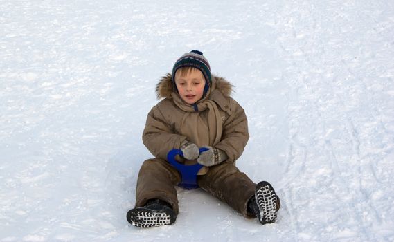 The boy goes for a drive on an ice slope.