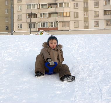 The boy goes for a drive on an ice slope in city park.