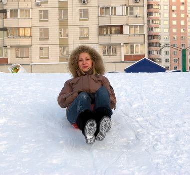 Young girl riding in a city park with a snow slide.