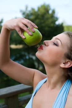 Girl with apple on sunset on green background