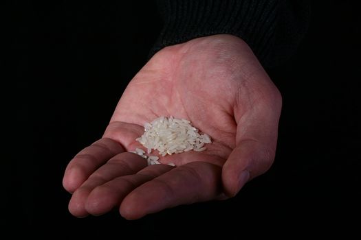 Man is hand with a small handful of rice on a black background.