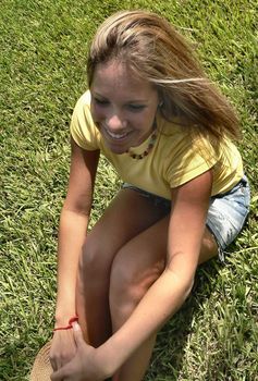 Happy teenager sitting on green grass enjoying the sun