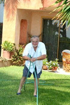 Elderly man crimping hose to change lawn sprinkler