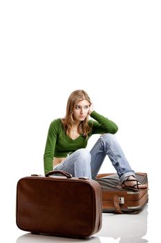 Beautiful young woman seated amd waiting with two old leather suitcases