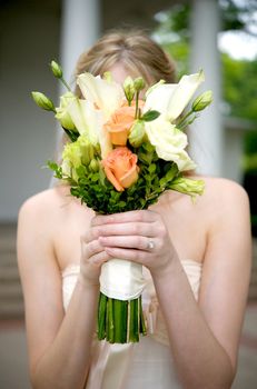 Image of a bride holding her bouquet over her face