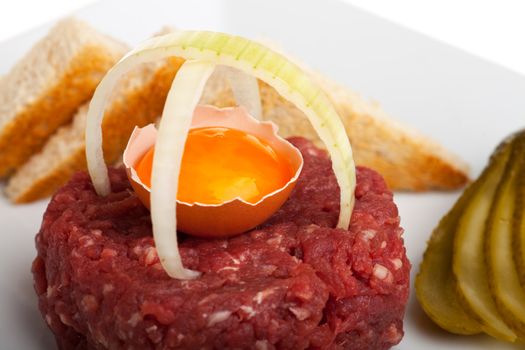 steak tartar with an onion ring and an open egg