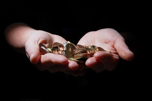 hands with money coins on a black background
