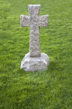 A stone cross surrounded by grass in a graveyard