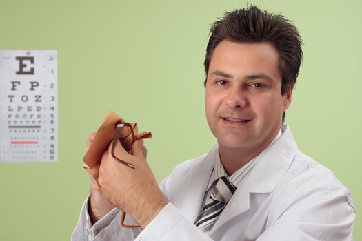 Friendly smiling optician, optometrist cleans a pair of eye glasses.