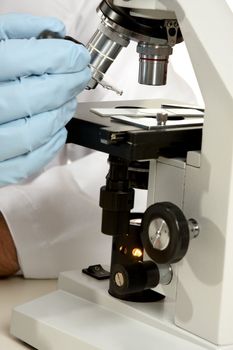 Closeup of a scientist, researcher or pharmacist using a dropper and microscope.