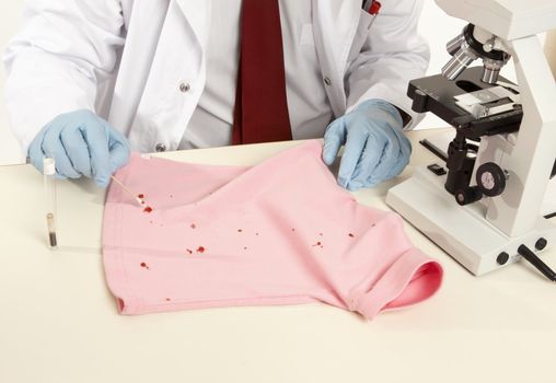 Closeup of a forensic expert swabbing and analysing a stain from a shirt.