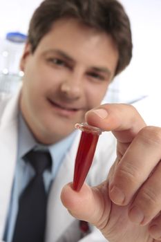 A male scientist or medical researcher holding a sample in a microcentrifuge tube.  Closeup with focus to hand and tube.