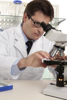 A researcher positions a slide under the microscope for study.