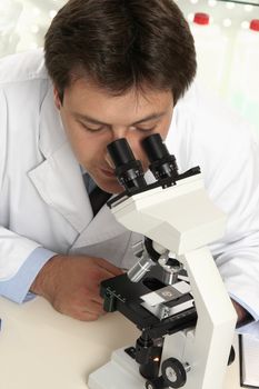 A scientist observes substance through microscope