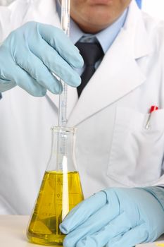 Scientist using a stirrer to mix liquids in flask.  Focus to hands.