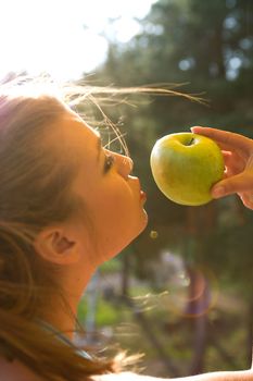 Girl with apple on sunset on green background