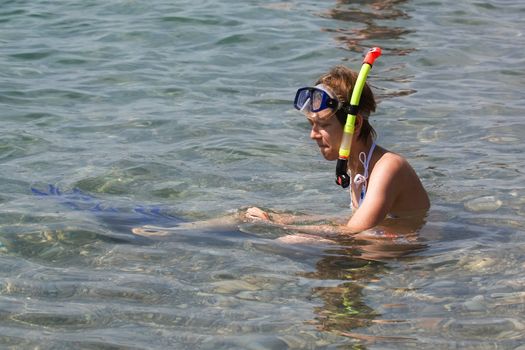 Young woman sitting in water with snorkel and fins