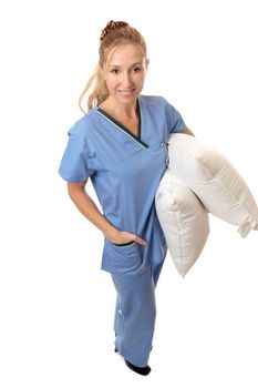 Confident female nurse or midwife carrying pillows for patients.  She is standing on a white background and has a friendly smile.