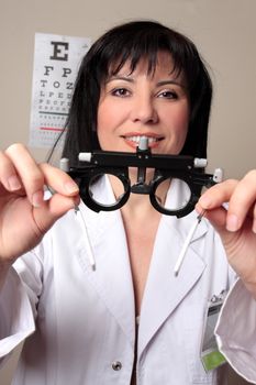 Optometrist or eye doctor about to put trial frames on a patient during a vision checkup.