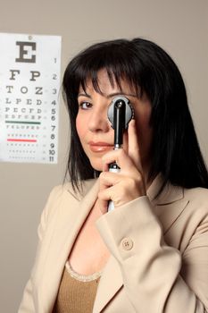 Optometrist using an opthalmoscope to check eyes.