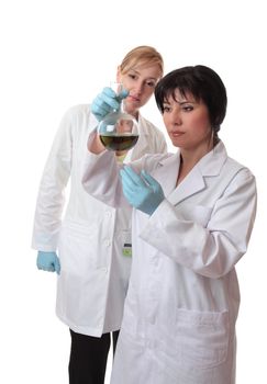Two female scientists analyse chemical mixture.