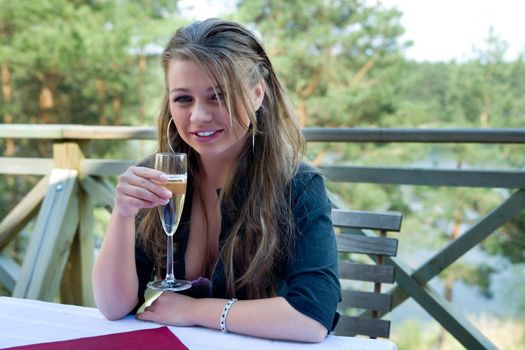 Young girl with glass of champagne on veranda