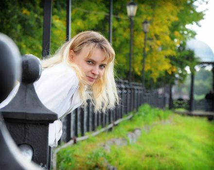 Beautiful blonde lady in overcoat walks around railing, quay