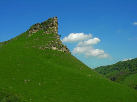 Covered  green grass rock on a background of the blue sky
          