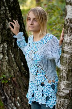 sunburned girl in blue pullover between two birches
