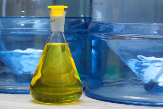Erlenmeyer flask with yellow liquid in chemistry lab (blue background)