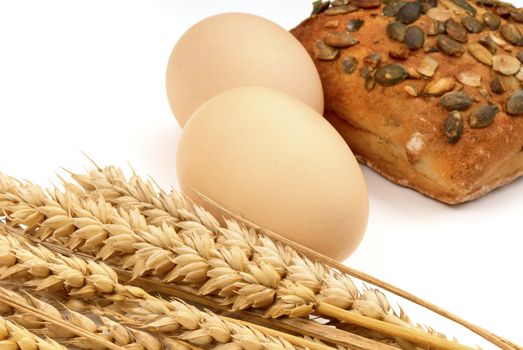 Wheat, eggs, and loaf on a white background. Macro.