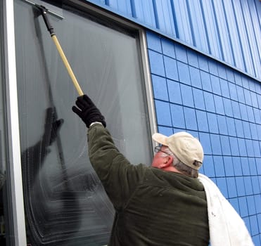 professional commercial window washer cleaning windows at a business