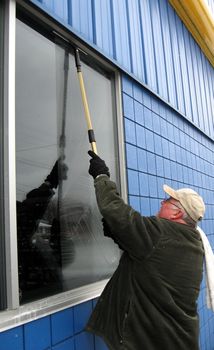 professional commercial window washer cleaning windows at a business 