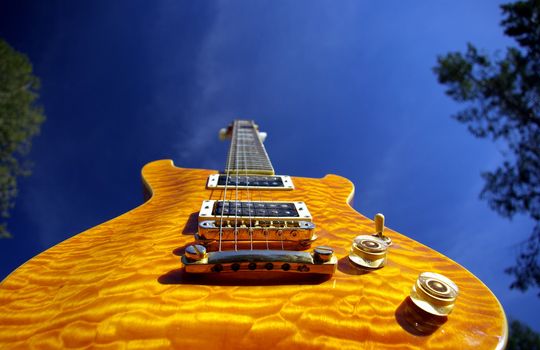 A pillow maple guitar body against a blue sky