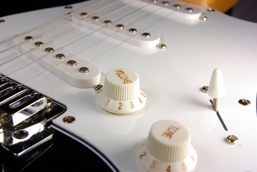 A black and white guitar viewed from the bridge towads the neck of the guitar