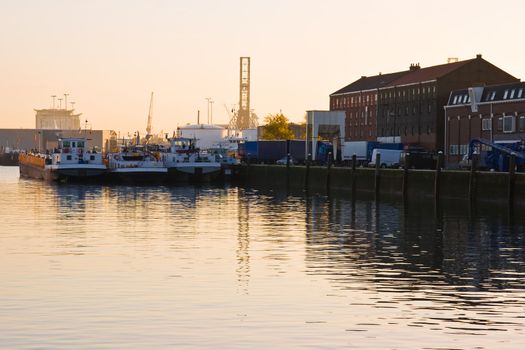 Ships and cranes with reflection in harbour at sunrise in autumn