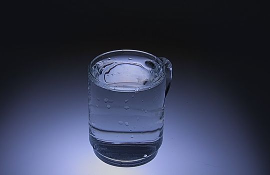 Glas of pouring water with reflection
