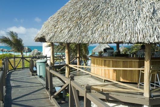 a palapa bar by the beach at a tropical resort