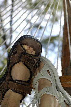 Male and female feet in sandals, snuggling up on a hammock