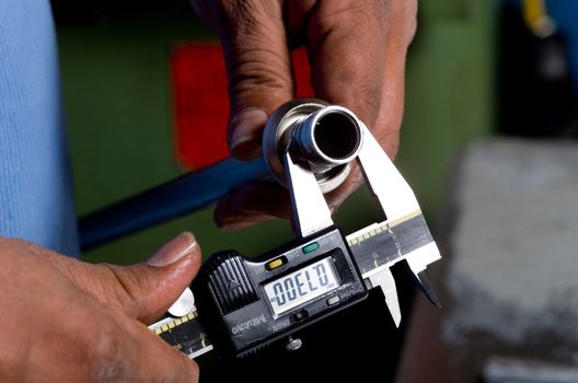Image of hands holding a tool measuring a pipe
