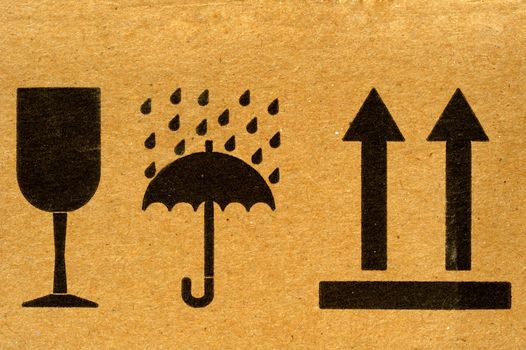 The symbols 'fragile', 'keep dry' and 'this way up' on cardboard.