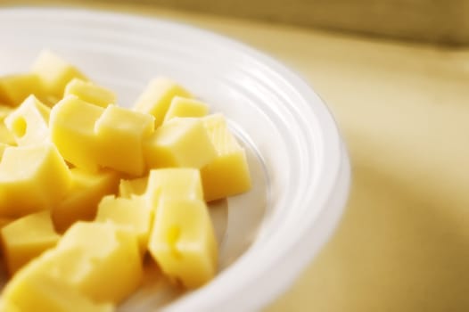 Cheese cubes in plastic dish with copy space, shallow depth of field and diffuse filter for dreamy look