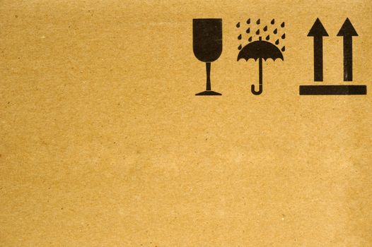 The symbols 'fragile', 'keep dry' and 'this way up' on the side of a cardboard box. Space for text on the cardboard. 