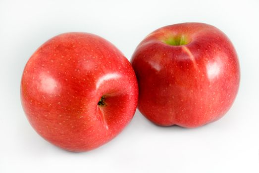 Two red apples are photographed on a white background