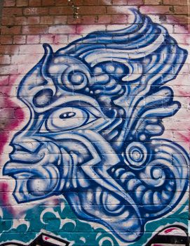 Graffiti mask in blue of man on wall in urban alley in Melbourne Australia, Victoria. Nice unblemished picture of a warrior face.