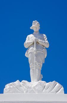 White war memorial for the fallen Australian soldiers in different wars of the 20th century. The soldier is wearing the typical Australian battle dress of the early 20th century. The statue stands against a blue sky. Western Australia.