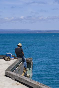 North-West Tasmania. A lonely fisherman chose the end of the quay to sit and fish. View over the bay from Stanley.