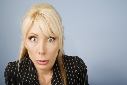 Close Up of an Apprehensive blonde businesswoman in front of a blue background