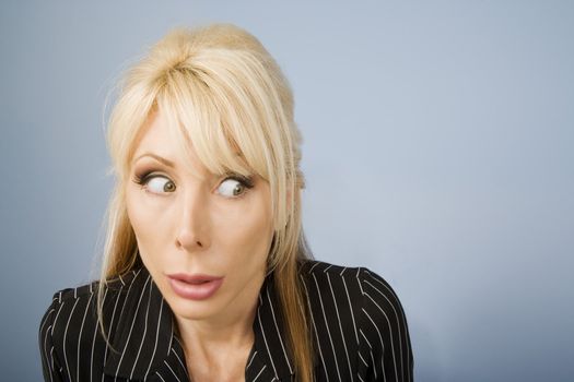 Close Up of an Apprehensive blonde businesswoman in front of a blue background